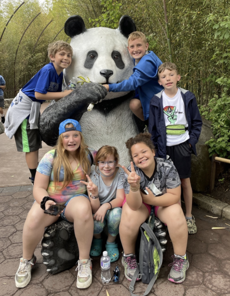 Kids posing with a panda statue 